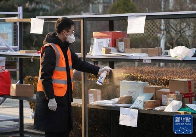 ↑1月18日，在百旺茉莉园一期外，工作人员对快递进行消毒。