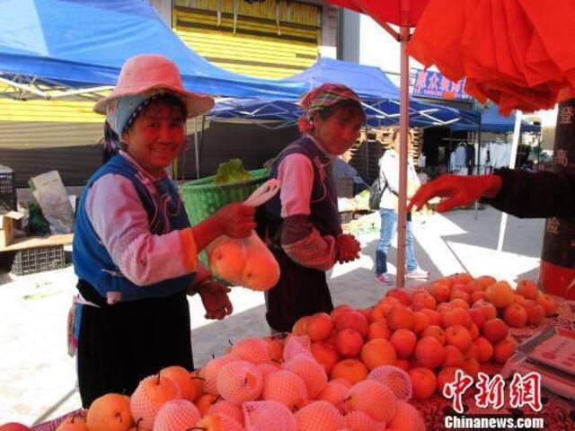资料图：村民在乡街购买水果。张丹摄