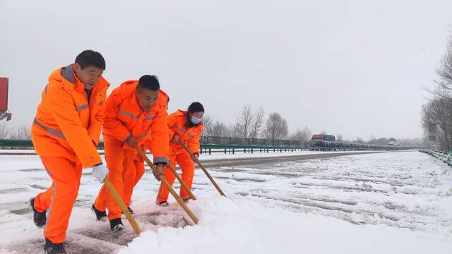 高速公路养护人员正在清理路面上的积雪。新华社发（李维轩摄）