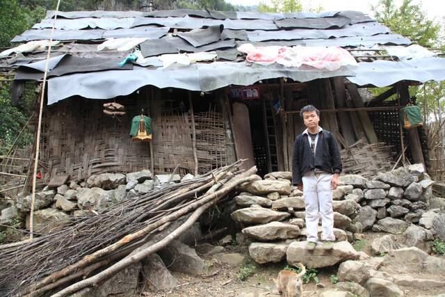 图为一名白裤瑶村民在自己的茅草房前。（南丹县委宣传部供图）