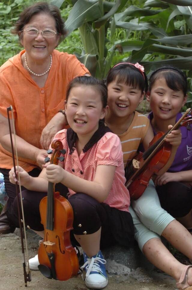邓小岚（左一）和孩子们在校外山间田野练习音乐间隙休息（2015年8月8日摄）。新华社发