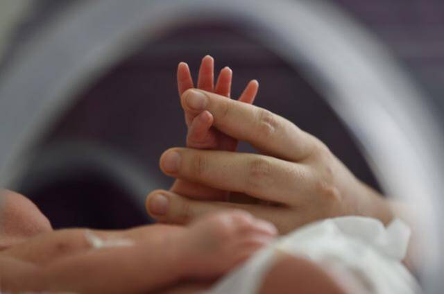2022年1月1日，医护人员跟一个新生儿握手。新华社方东旭摄。
