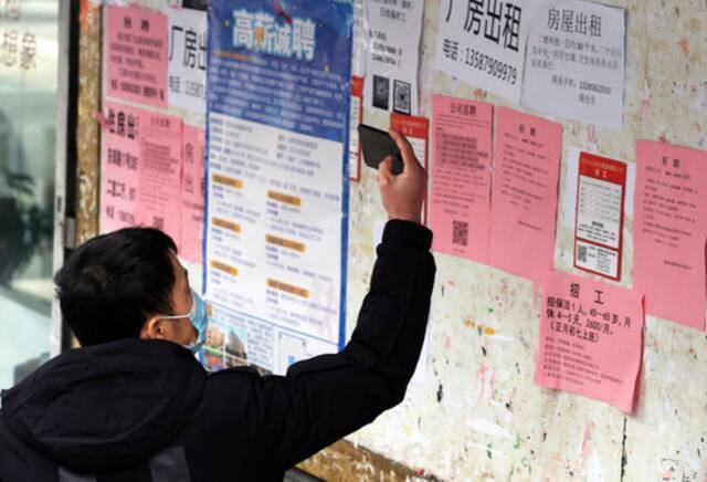 居民在拍摄招工广告资料图据视觉中国