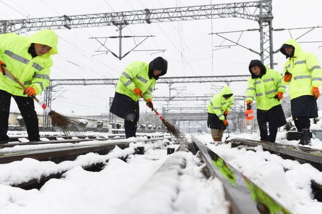  2月7日，合肥站工作人员在清扫道岔积雪，确保站区铁路设备状态良好，列车接发正常。新华社图