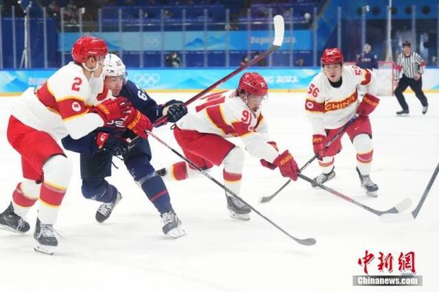 2月10日，在国家体育馆举行的北京2022年冬奥会男子冰球小组赛中，中国队对阵美国队。图为中国队球员和美国队球员在比赛中拼抢。中新社记者毛建军摄