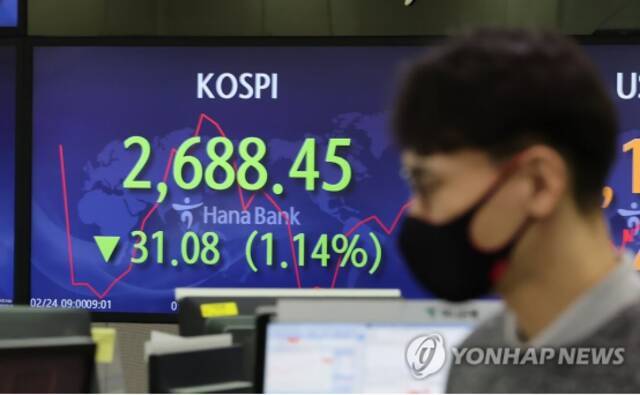 2月24日上午，在首尔市中区韩亚银行，交易员走过实时股价显示屏。（图源：韩媒）