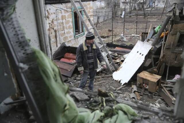 2月24日，乌克兰东部炮击发生后，一名当地公民站在房屋废墟之间。图源：美联社