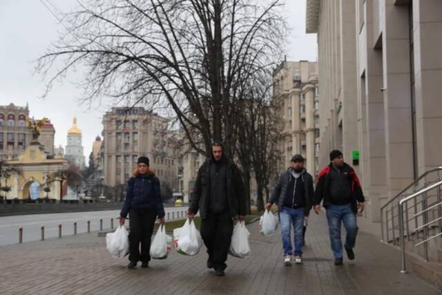 2月24日，在乌克兰基辅，当地居民拎着采购的物资走在街道上。新华社记者李东旭摄
