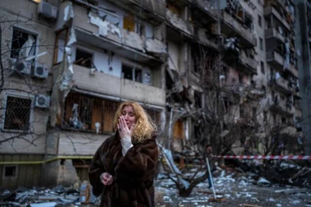 2月25日，基辅市遭俄军火箭弹袭击后，一名当地居民在被击毁的房子前哭泣。