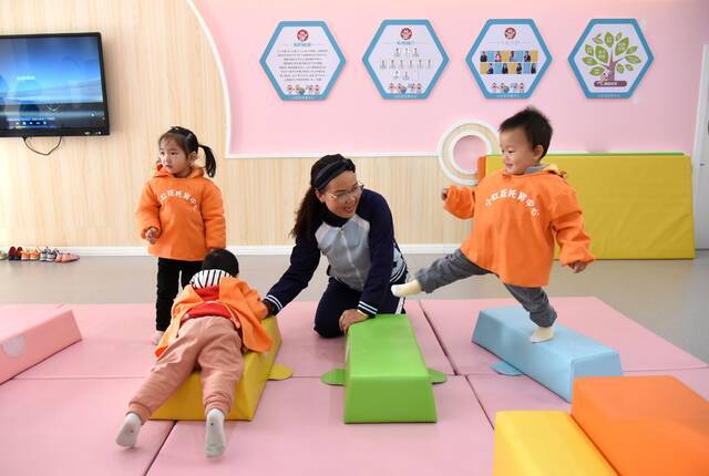 连云港市海州区新海街道小红花托育中心，婴幼儿在老师帮助下快乐地做游戏。图/IC photo