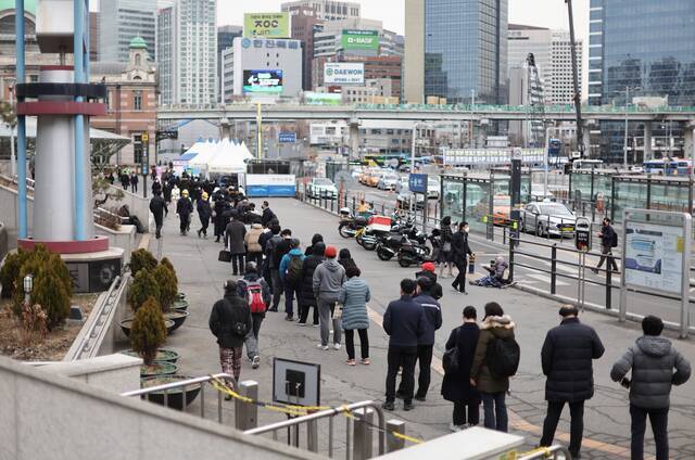 当地时间2022年3月8日，人们在韩国首尔车站前的一家筛查诊所排队接受检测。图丨视觉中国