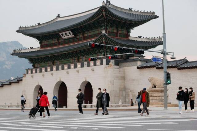 2021年11月29日，行人佩戴口罩在韩国首尔光化门过马路。新华社记者王益亮摄