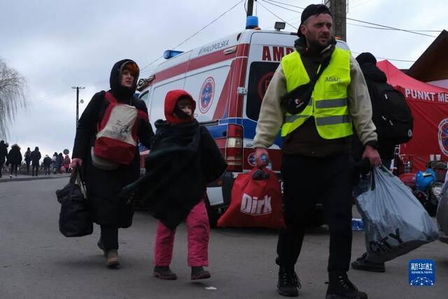 ·2月28日，一名志愿者陪同来自乌克兰的人们离开波兰梅迪卡口岸。（新华社记者孟鼎博摄）