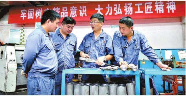 胡中辉(左三)向工友们讲解加工工艺