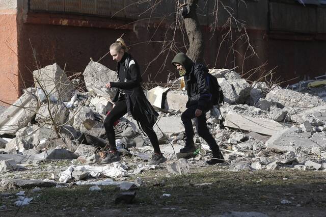 ↑3月23日，当地居民从马里乌波尔被损坏的建筑旁走过。新华社发（维克托摄）