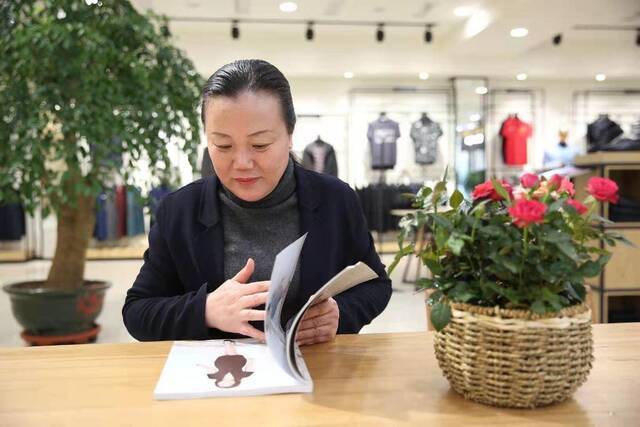 容城县罗萨服饰有限公司负责人李迎春在研究服装设计。（受访者供图）