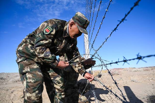 2020年秋，哈达布和在边境线上修补铁丝网。新华社记者刘磊摄