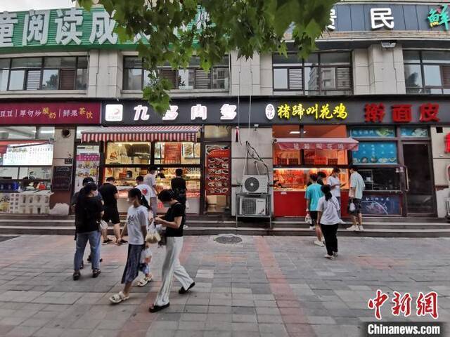 资料图：市民在街边小店购买小吃。韩章云摄