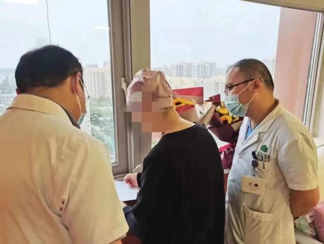 ▲2021年6月，医务社工团队为林平送上向日葵和木棉花花束，医生李志刚（右一）站在戴着“小花帽”的林平身旁。受访者供图