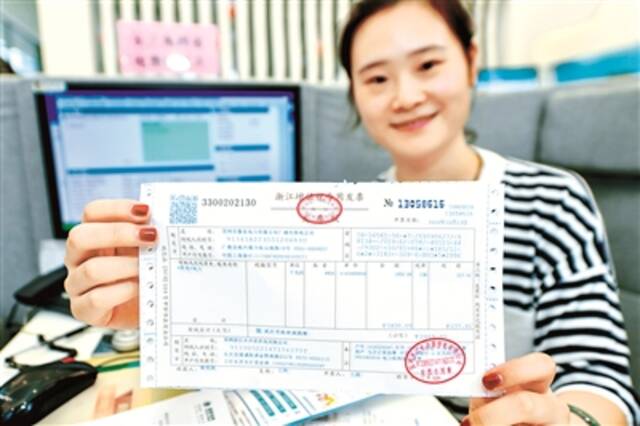浙江省湖州市长兴供电营业厅，工作人员正在展示刚刚办理的来自安徽广德的电费增值税专用发票。  (图片来源：视觉中国)