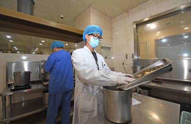 天津中医药大学第一附属医院，药师将药材放入容器中准备煎煮。（新华社记者赵子硕摄）
