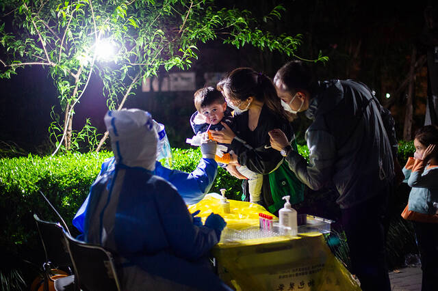 2022年4月9日，上海普陀区中远两湾城，一名儿童在父母的陪护下做核酸采样。