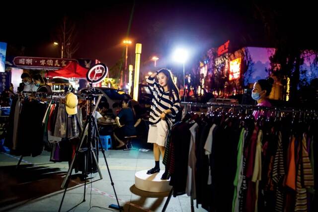 6月28日，山东滨州市万达广场，服装店主在夜市上通过网络直播售货。图/人民视觉