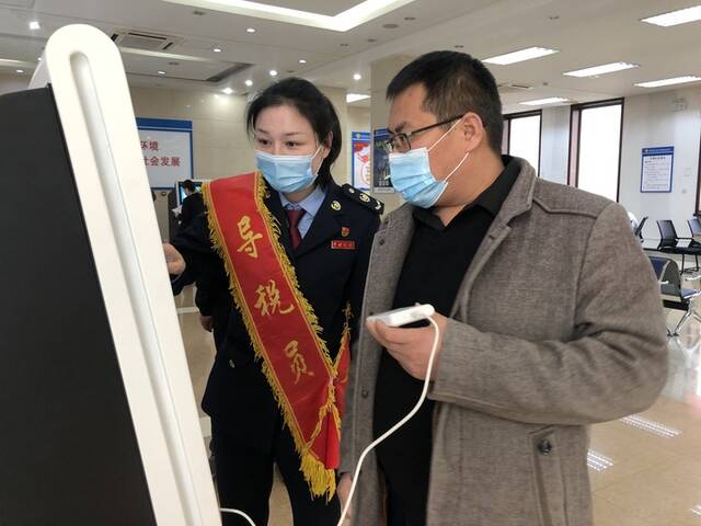 天津市静海区税务局工作人员指导企业财务人员申领增值税电子发票（资料照片）。受访者供图