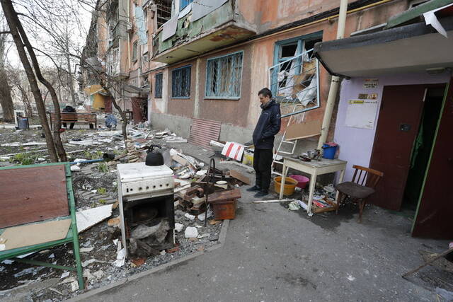 4月17日，在马里乌波尔，当地居民站在被损坏的建筑旁。新华社发（维克托摄）
