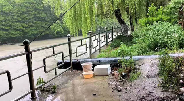 雨天，张扬扬放了箱子、盆子和桶在河边接水。