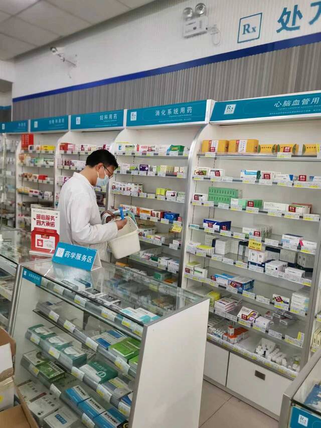 李中州在货架前根据订单拿药。受访者供图