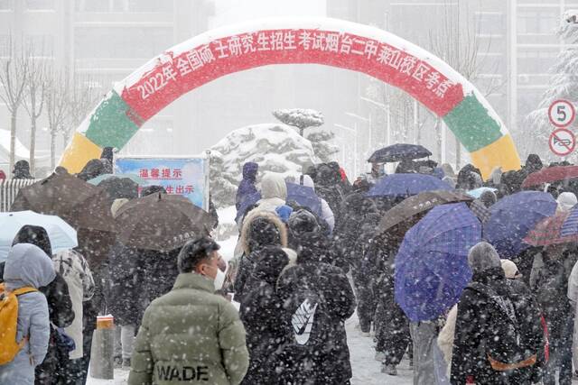  2021年12月25日，山东烟台，参加研究生考试的考生们顶风冒雪进入山东烟台二中莱山校区考点图源：视觉中国