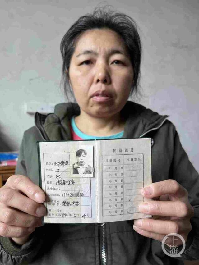 ▲邓群莲拿着自己当年的团员证。摄影/上游新闻记者萧鹏