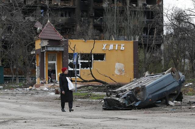 ↑4月21日，在马里乌波尔，当地居民从被损坏的汽车旁经过。新华社发（维克托摄）