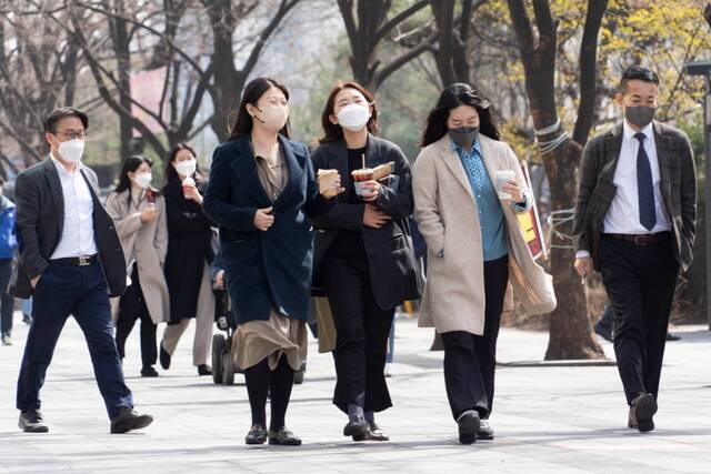 3月16日，人们佩戴口罩走在韩国首尔街头。新华社发（李相浩摄）