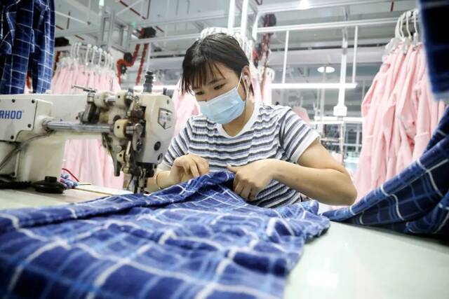 2021年7月11日，浙江桐庐，工人在制作浴袍和睡衣。图/视觉中国