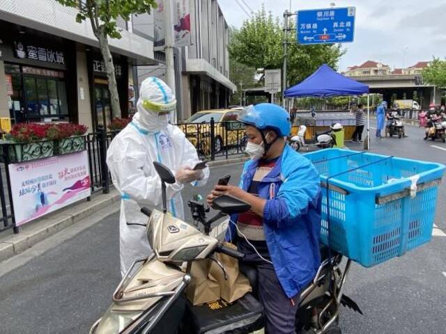 图说：普陀公安分局民警对配送寄递人员电子通行证进行核验。警方供图