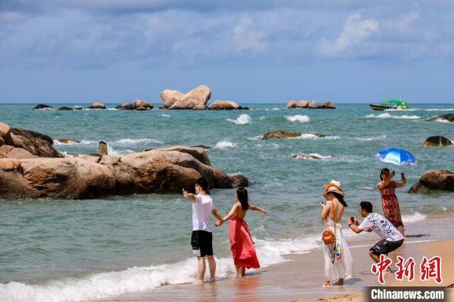 资料图：游客在天涯海角的海边沙滩“拥抱大海”。范勇摄