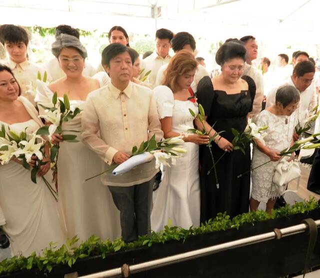 ·2016年，小马科斯和家庭成员在父亲墓前献花。