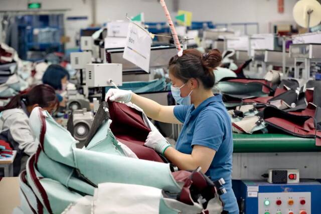 3月13日，江苏南通综合保税区一家企业内，工作人员在车间生产特斯拉、英菲尼迪等品牌配套的汽车座椅面套。图/IC