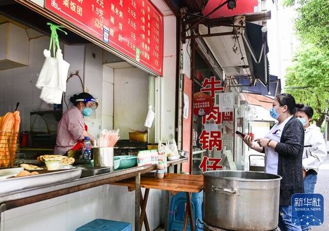 在上海市嘉定区新成路街道，居民在一家蛋饼店前排队（5月9日摄）。