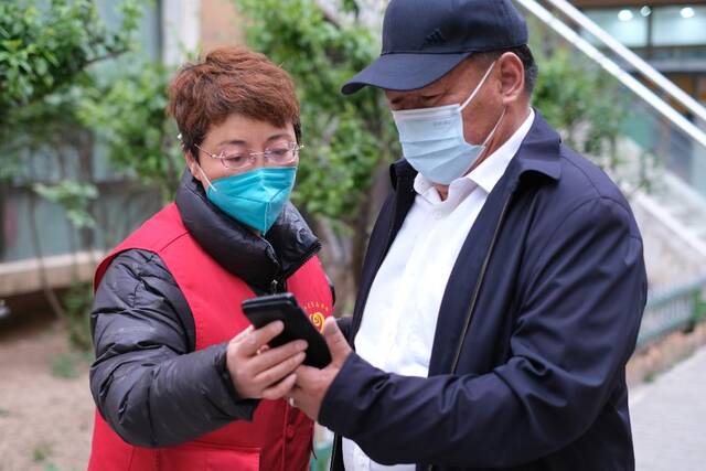 5月13日，张梅在西宁市城西区阳光华府小区核酸检测点查验居民的健康码和行程码。（新华社记者童昊摄）