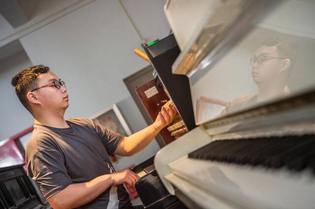 工人在修复技术中心对古董钢琴进行调音处理。新华社记者伍志尊摄