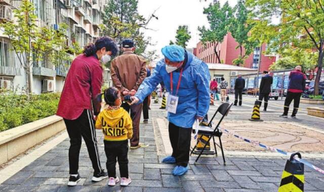 在核酸检测现场,北京市石景山区检察院干警为群众测量体温。记者闫昭通讯员成于庆摄