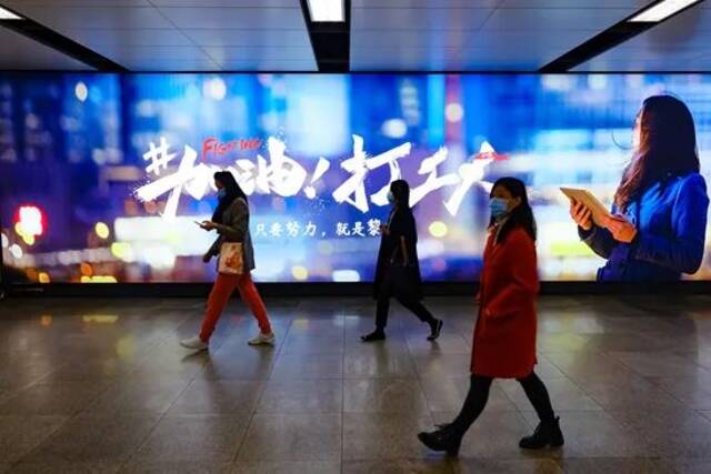深圳，行人从地铁通道内“加油打工人”主题广告前走过。视觉中国供图