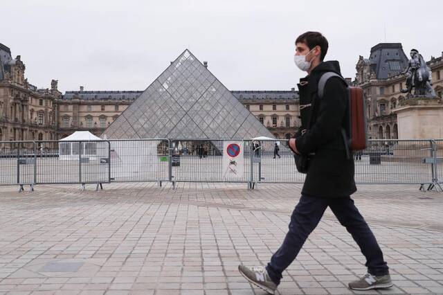 1月19日，一名男子走过法国巴黎卢浮宫的玻璃金字塔。新华社记者高静摄