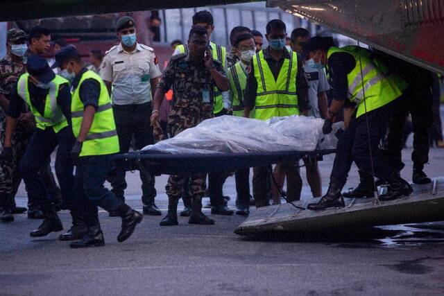 5月30日，在尼泊尔加德满都的一座机场，救援人员运送遇难者遗体。新华社发（苏拉韦·什雷斯塔摄）