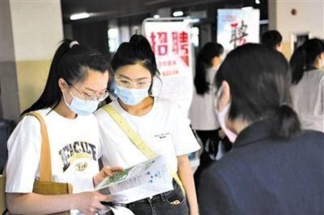 在合肥学院内，求职者现场了解招聘信息。