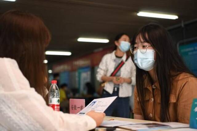 5月17日，在合肥学院内，求职者（右）向用人单位工作人员了解招聘信息。新华社记者张端摄