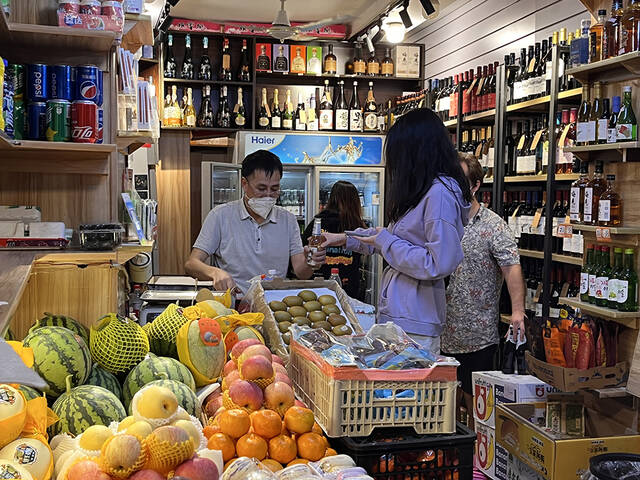 6月1日0点20分左右，上海长乐路上一家烟酒水果店，老板为一位顾客开啤酒。澎湃新闻记者邹佳雯图